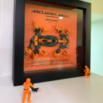 Framed three-dimensional artwork depicting the McLaren MCL38 with pit-crew figures
